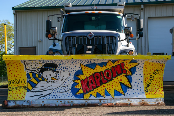 Medill Elementary’s winner of the 2025 People’s Choice Award, featuring a blade with a cartoon snowman, swirling snowflakes, and a comic-style exclamation ‘KAPLOW!’